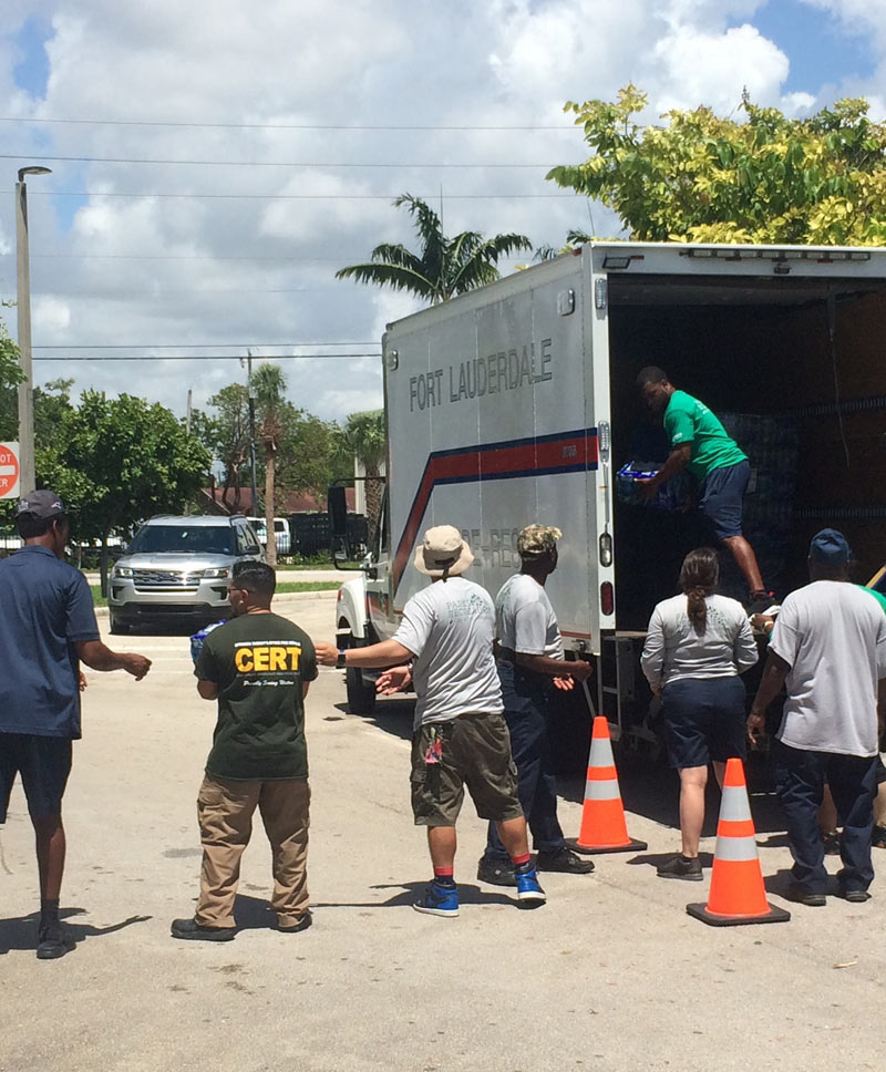 People helping unloading cases of water from a truck